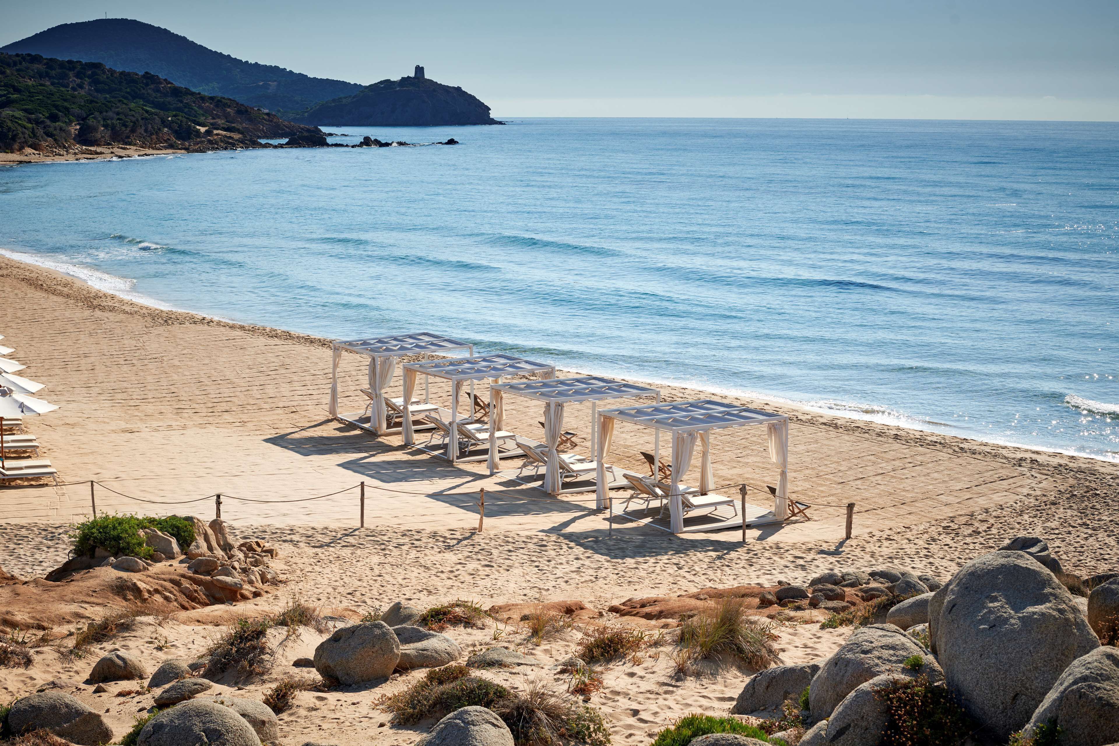 A beach with a row of white sun loungers and a rope barrier.