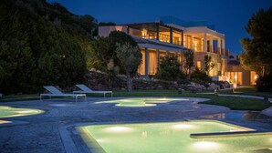 Ein modernes Haus mit Poolbereich, inklusive Liegestühlen und einem gut beleuchteten Schwimmbad.