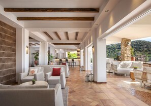 A spacious indoor area with a long corridor, seating arrangements, and a view of the outdoors.
