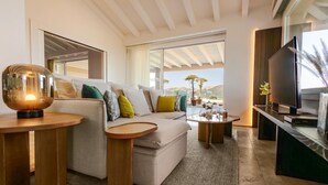 Ein modernes Wohnzimmer mit einer Couch, einem Couchtisch, einem Fernseher und einem großen Fenster mit Blick.