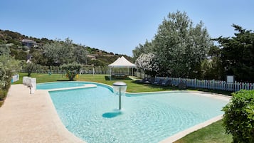 Relax by the serene pool surrounded by lush greenery and a well-maintained lawn.