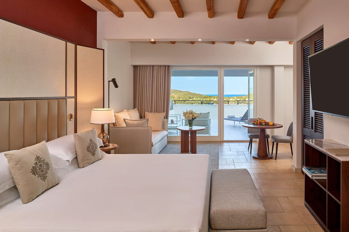 Een hotelkamer met een groot bed, een bank, een eettafel en een televisie.