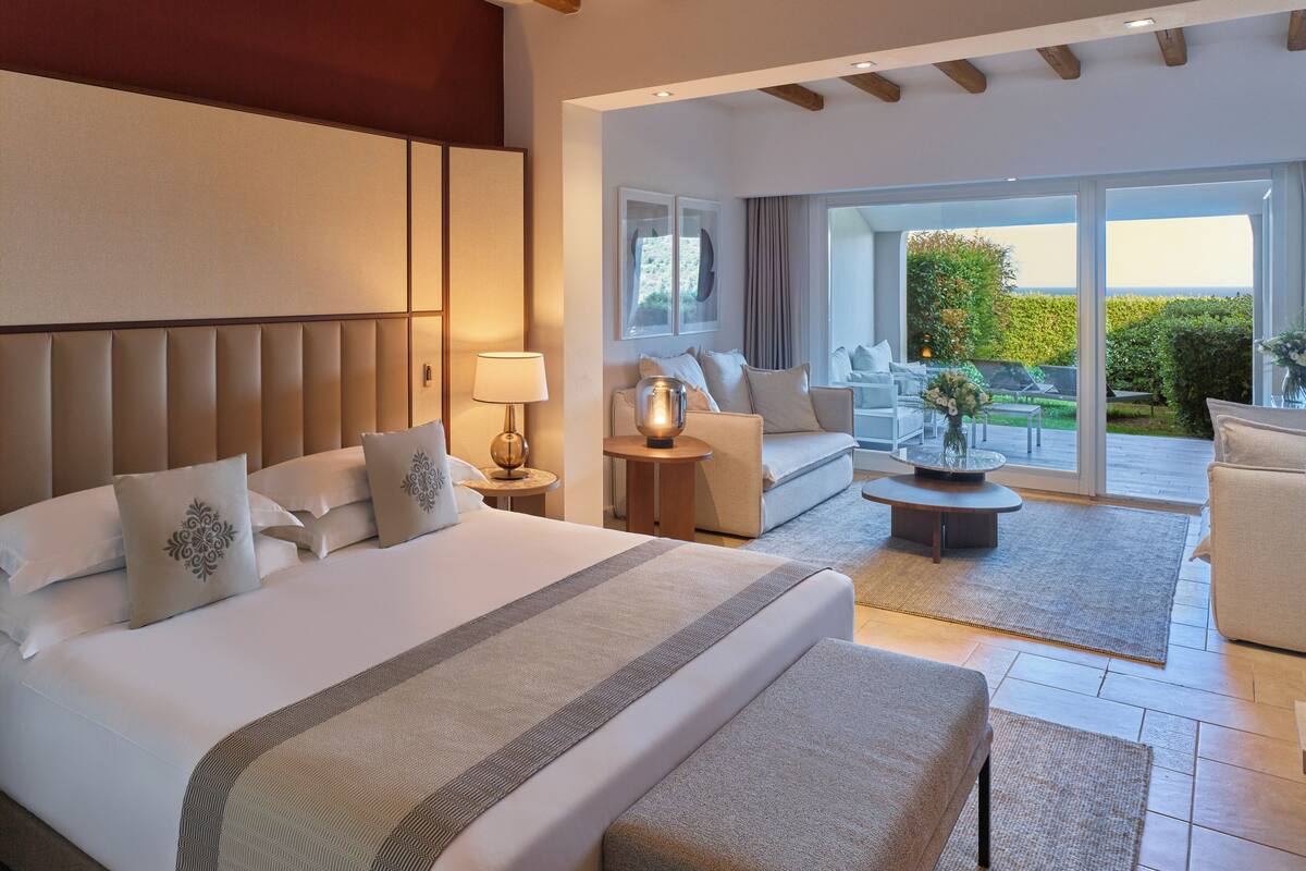 Een moderne hotelkamer met een groot bed, een bank, een bijzettafeltje en een balkon met uitzicht.