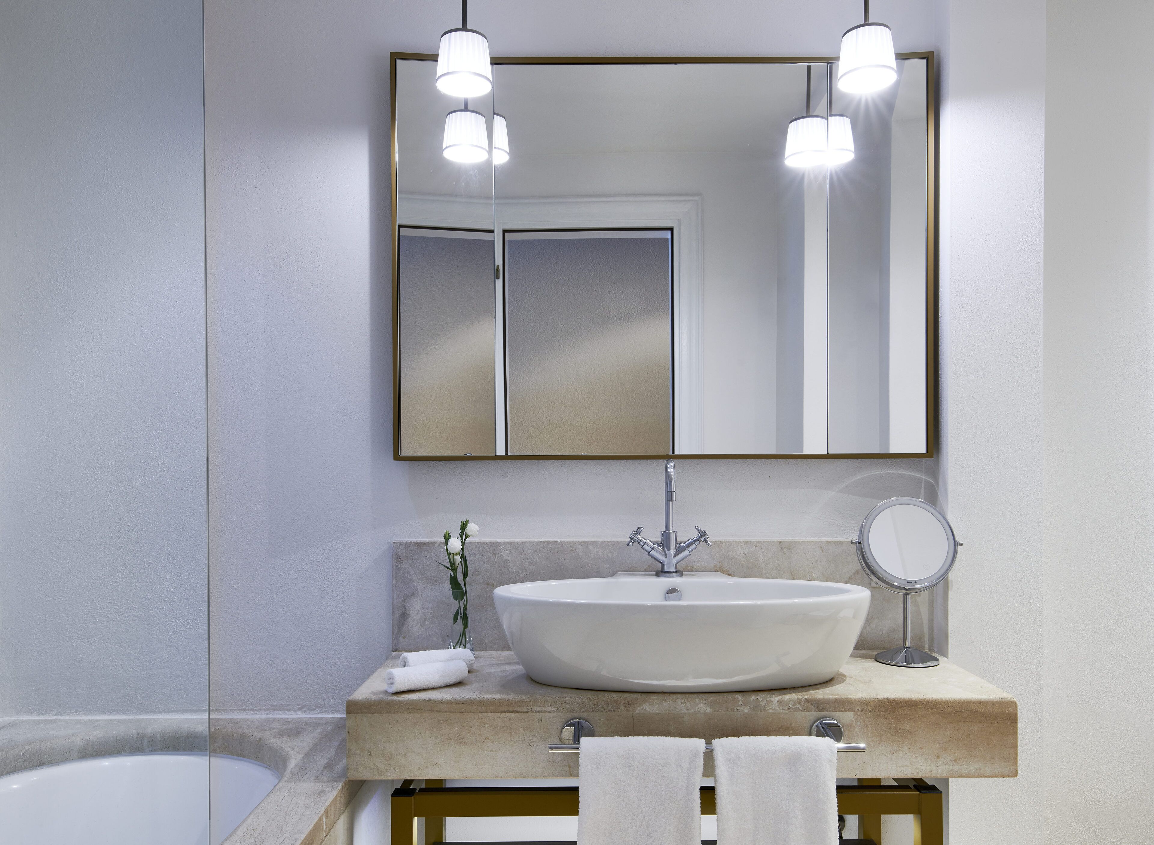 Un baño moderno con un espejo grande, un lavamanos blanco y una bañera.