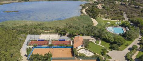 Una propiedad costera con cancha de tenis, piscina y vista al mar.