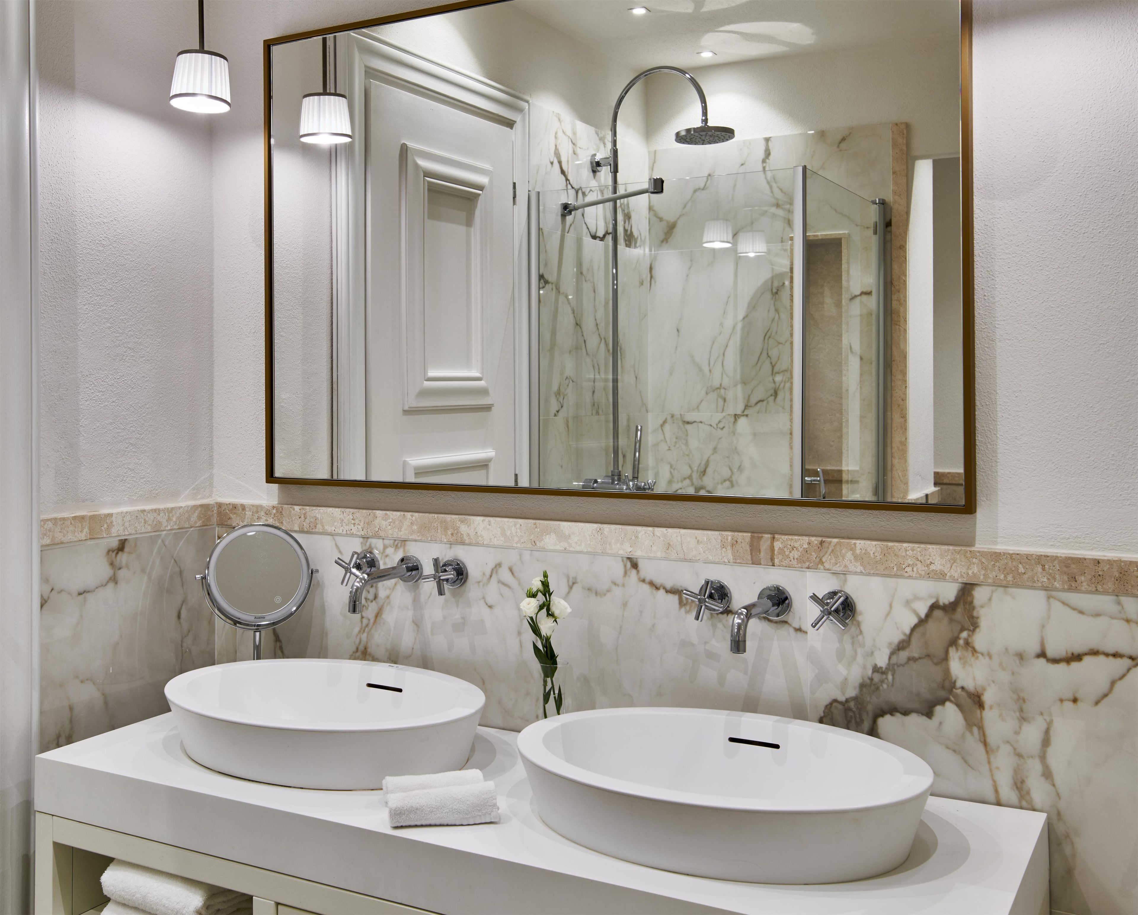 Un baño con dos lavamanos redondos, un espejo y una ducha.