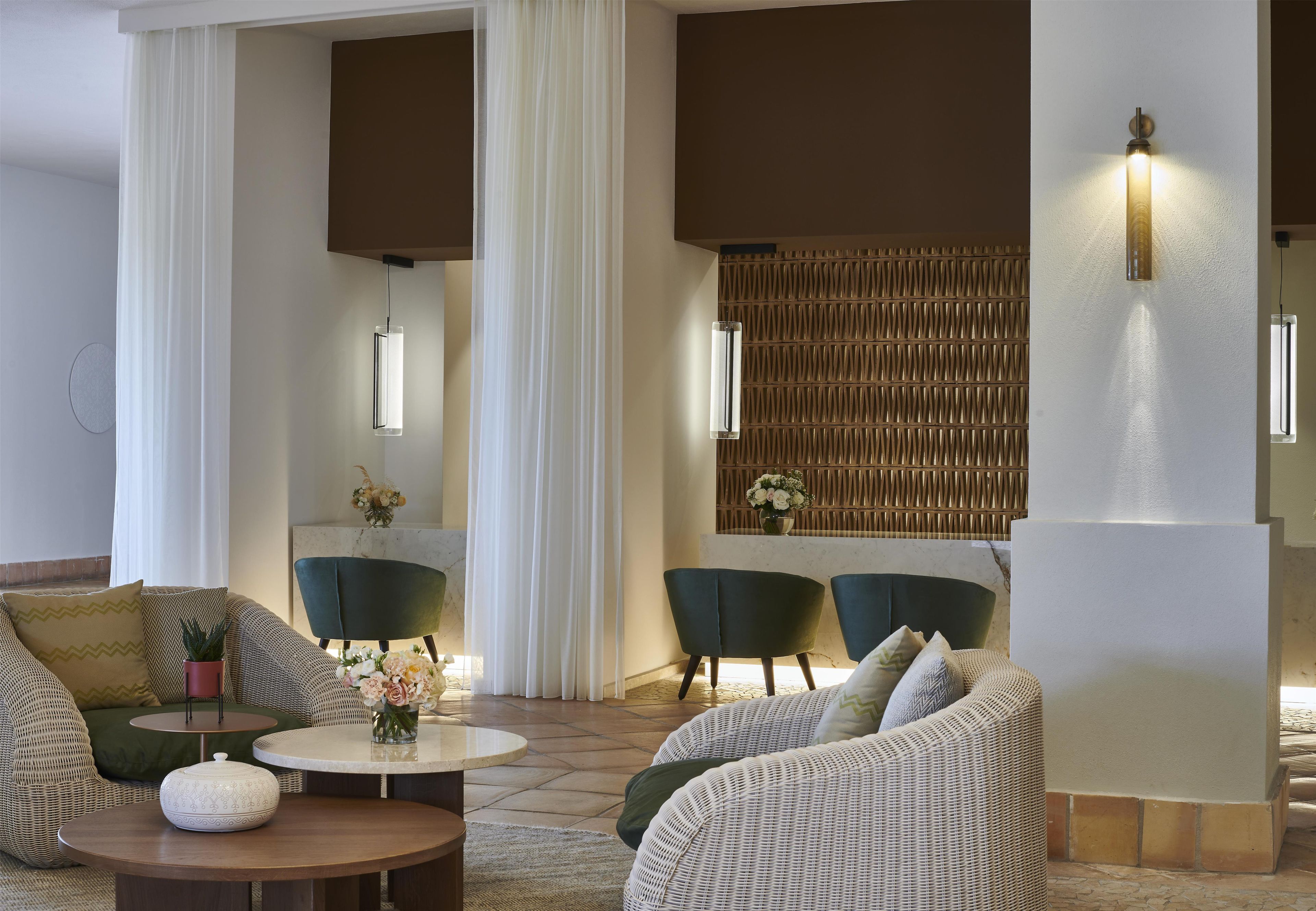 A modern lounge area with wicker furniture, a marble table, and a decorative wall with a patterned panel.