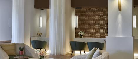 A modern lounge area with wicker furniture, a marble table, and a decorative wall with a patterned panel.