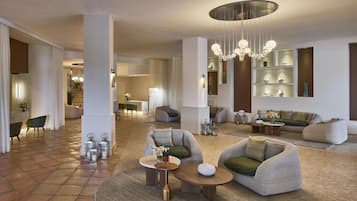 Un vaste espace de vie doté d’un plafond haut, de meubles modernes et d’un lustre central.