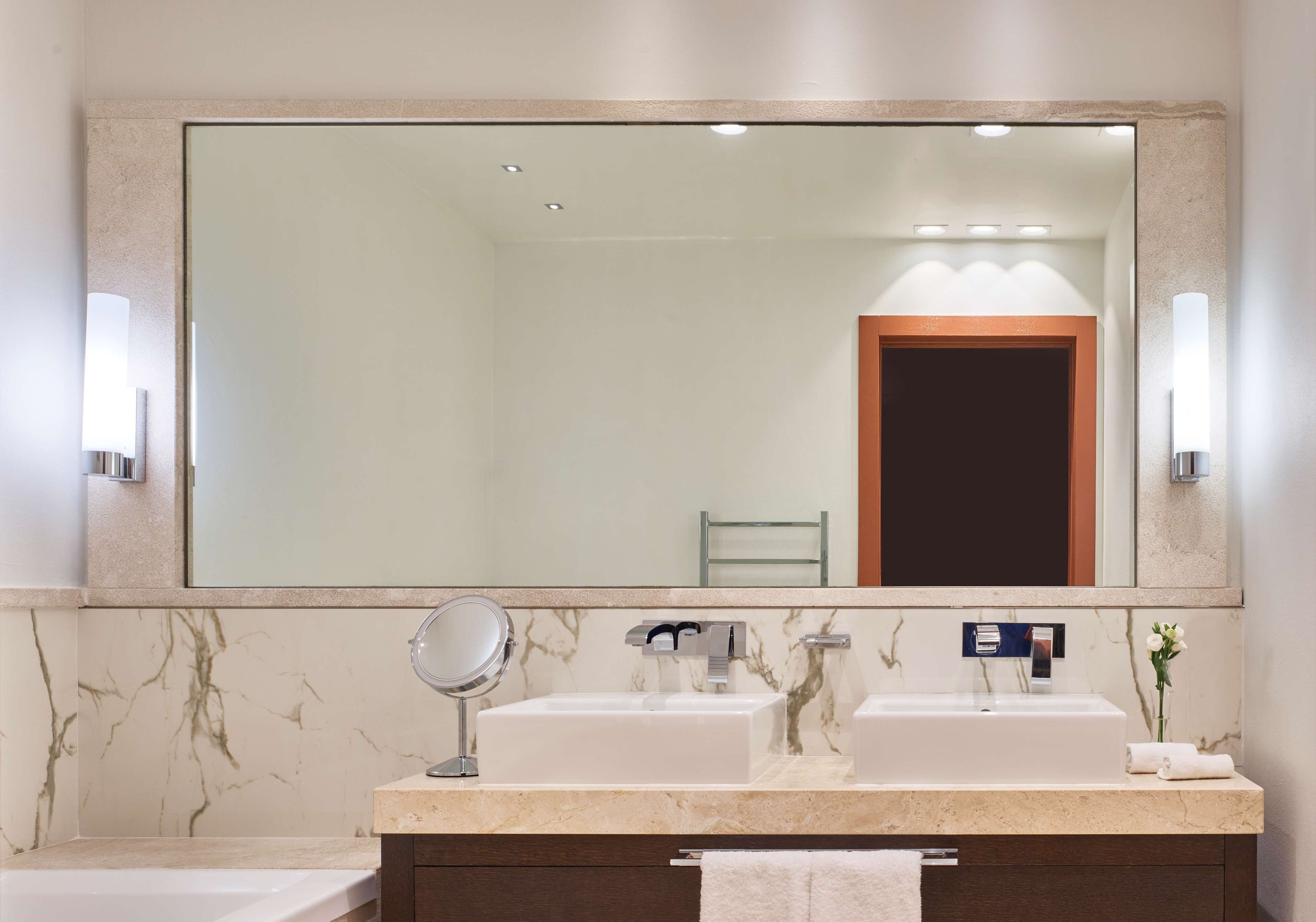 A bathroom with two sinks, a mirror, and a towel rack.