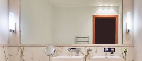 A bathroom with two sinks, a mirror, and a towel rack.