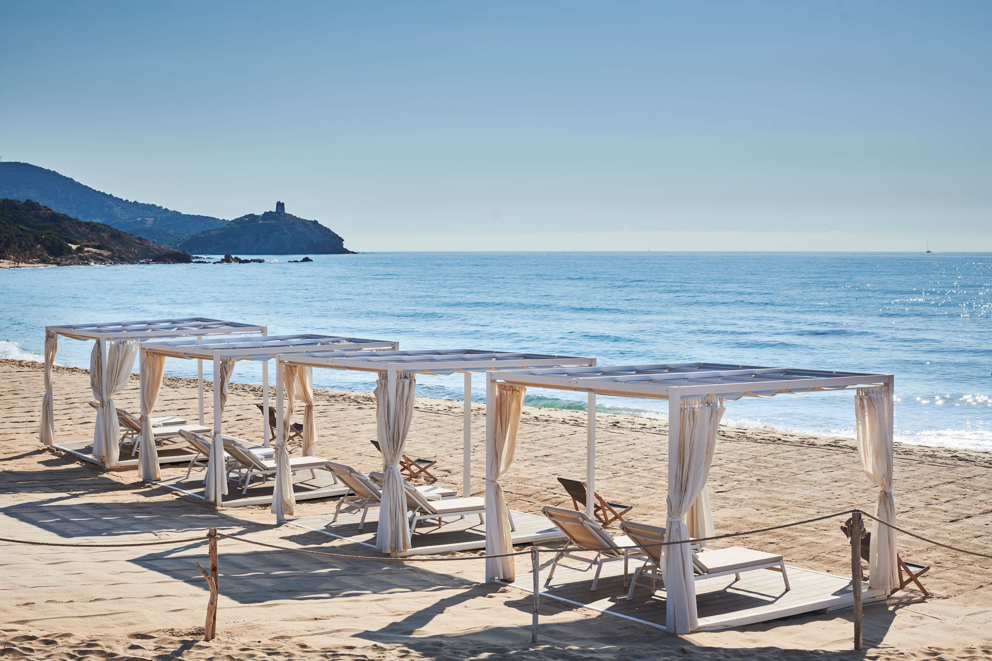 A beach with white canopies and lounge chairs.