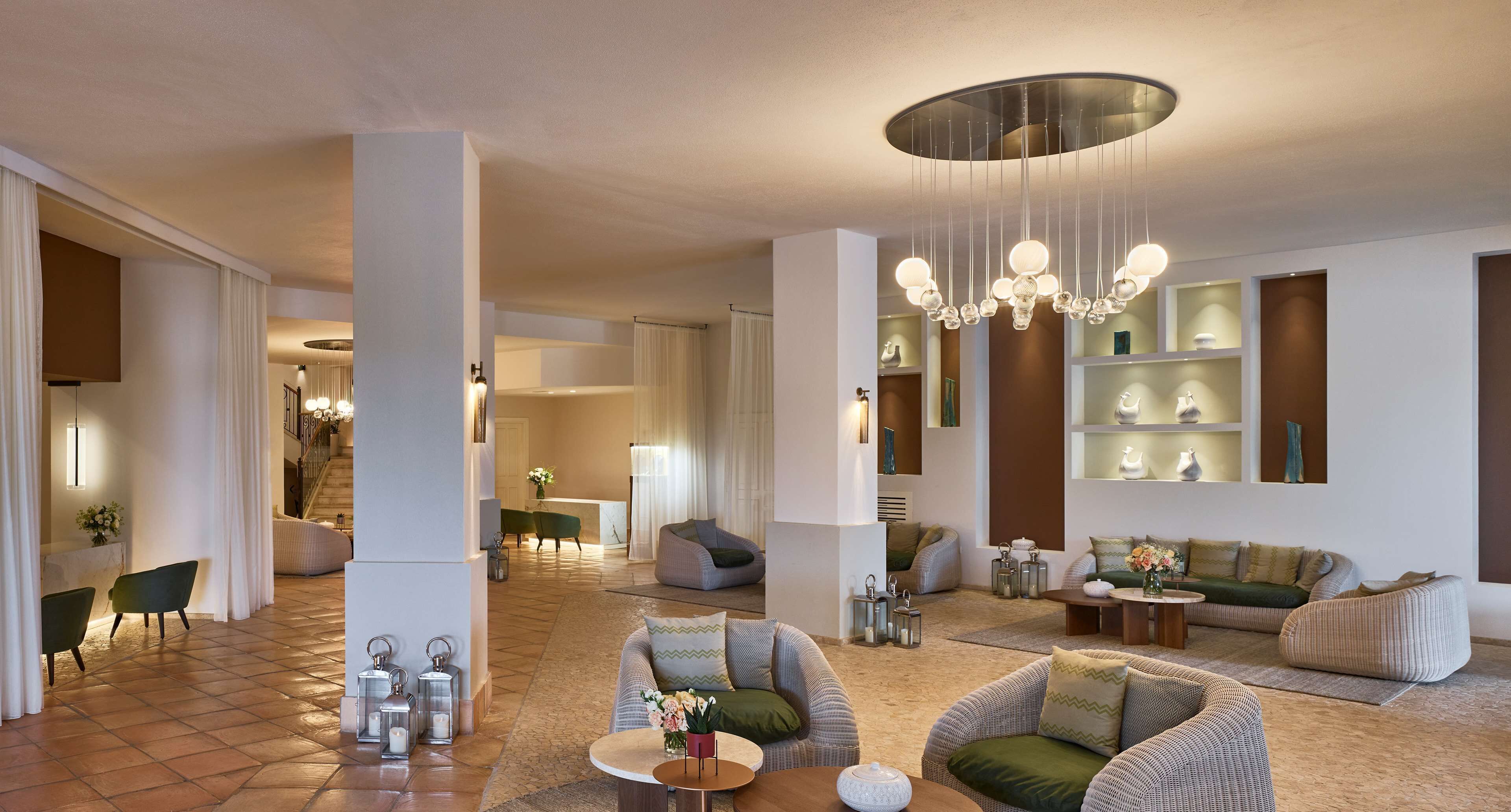 A spacious living area with modern furniture, a chandelier, and decorative items on shelves.