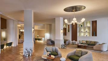 A spacious living area with modern furniture, a chandelier, and decorative items on shelves.