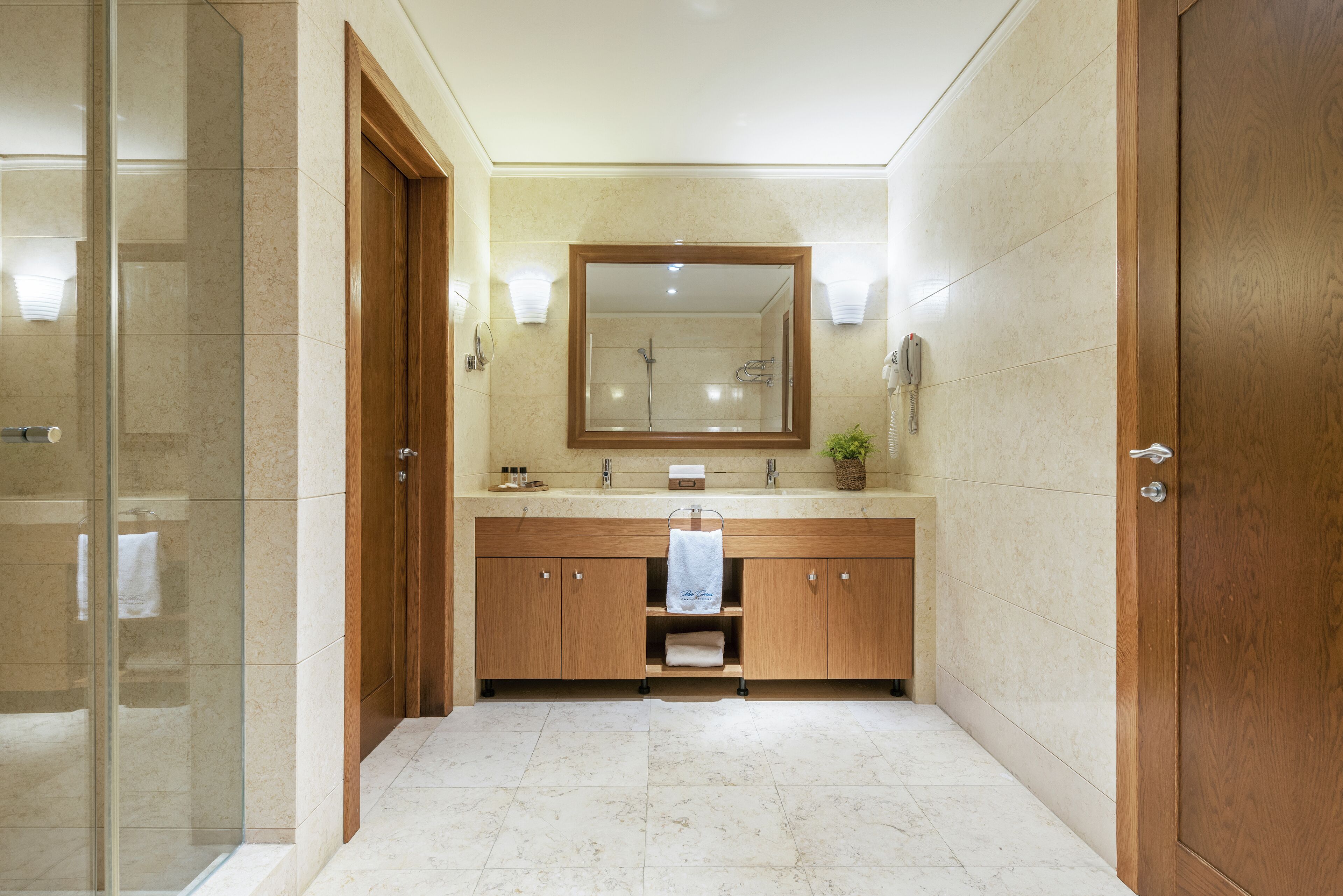 Un baño moderno con cabina de ducha de vidrio, tocador de madera y un espejo grande.