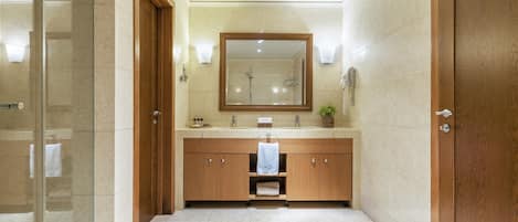 Un baño moderno con cabina de ducha de vidrio, tocador de madera y un espejo grande.