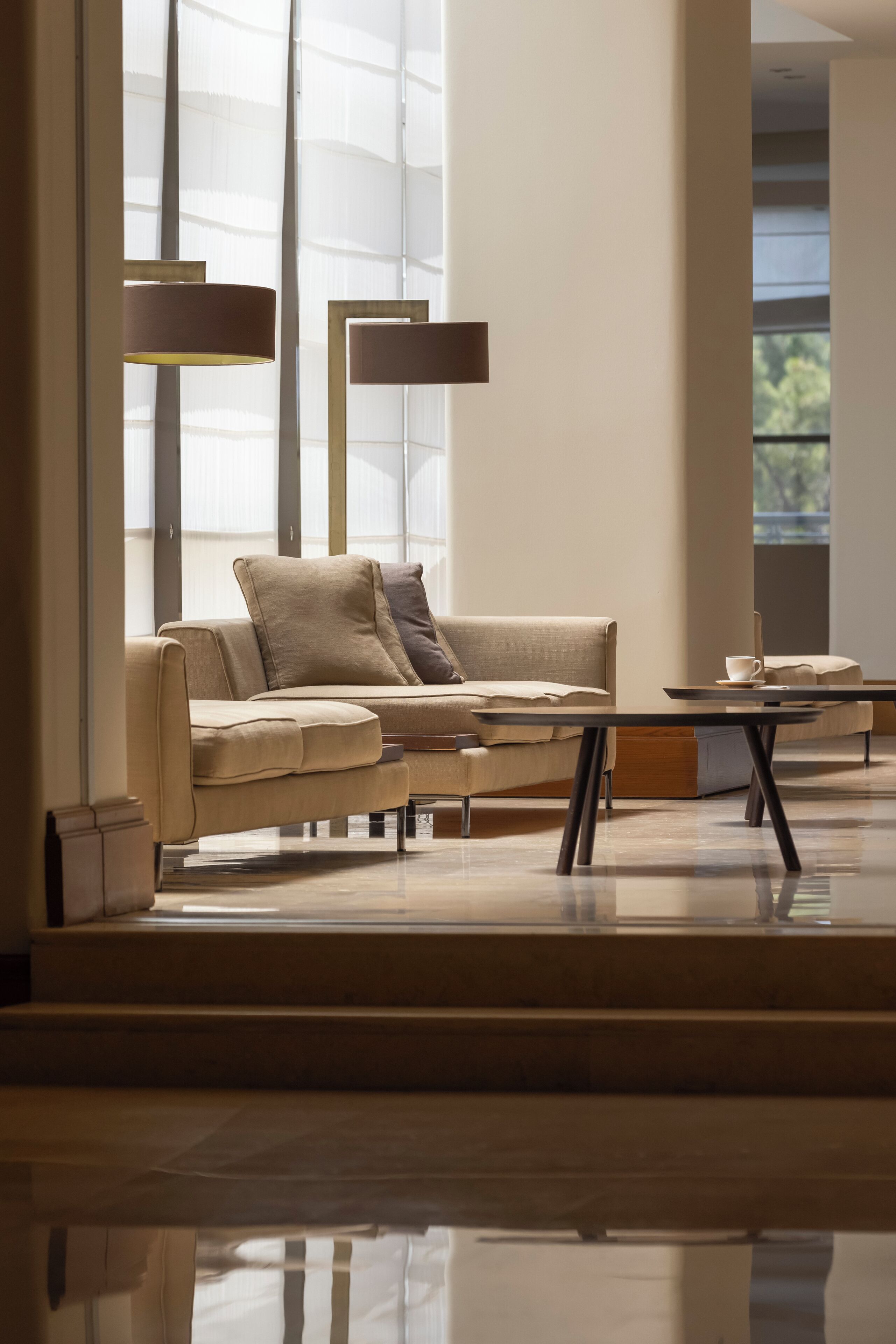 A modern living room with a beige sofa, a coffee table, and floor lamps.