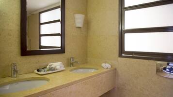 Baño con dos lavamanos, un espejo y una ventana.
