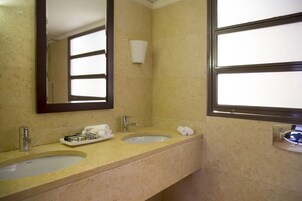 Baño con dos lavamanos, un espejo y una ventana.