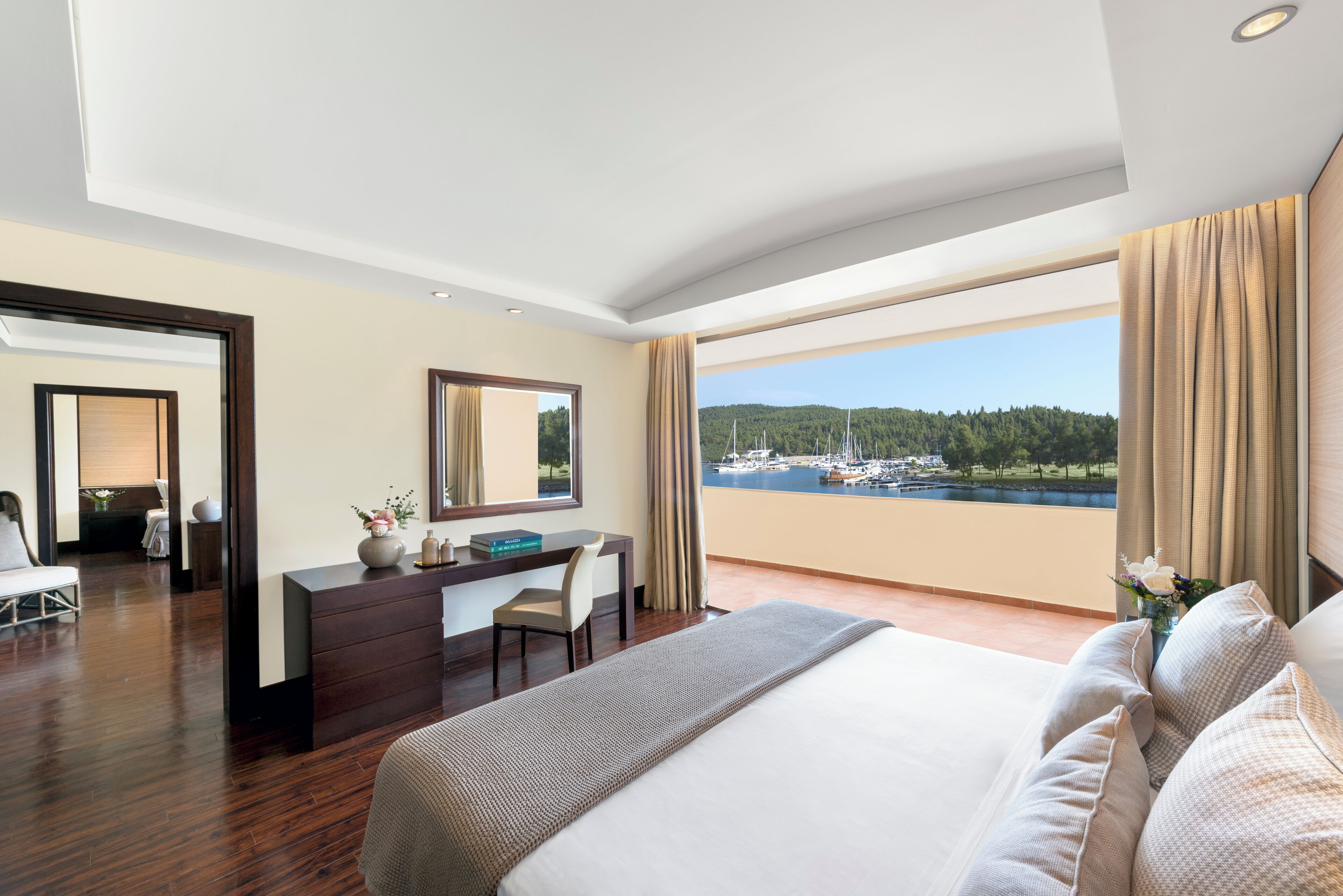 A hotel room with a large bed, a desk, and a view of a marina.