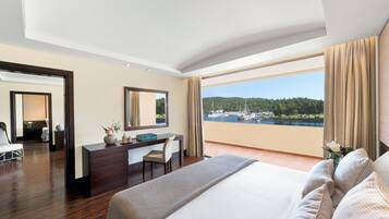 A hotel room with a large bed, a desk, and a view of a marina.