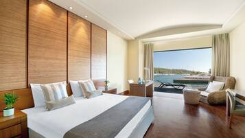 Habitación de hotel moderna con una cama grande, un área de descanso con vistas al mar y un balcón con piscina.