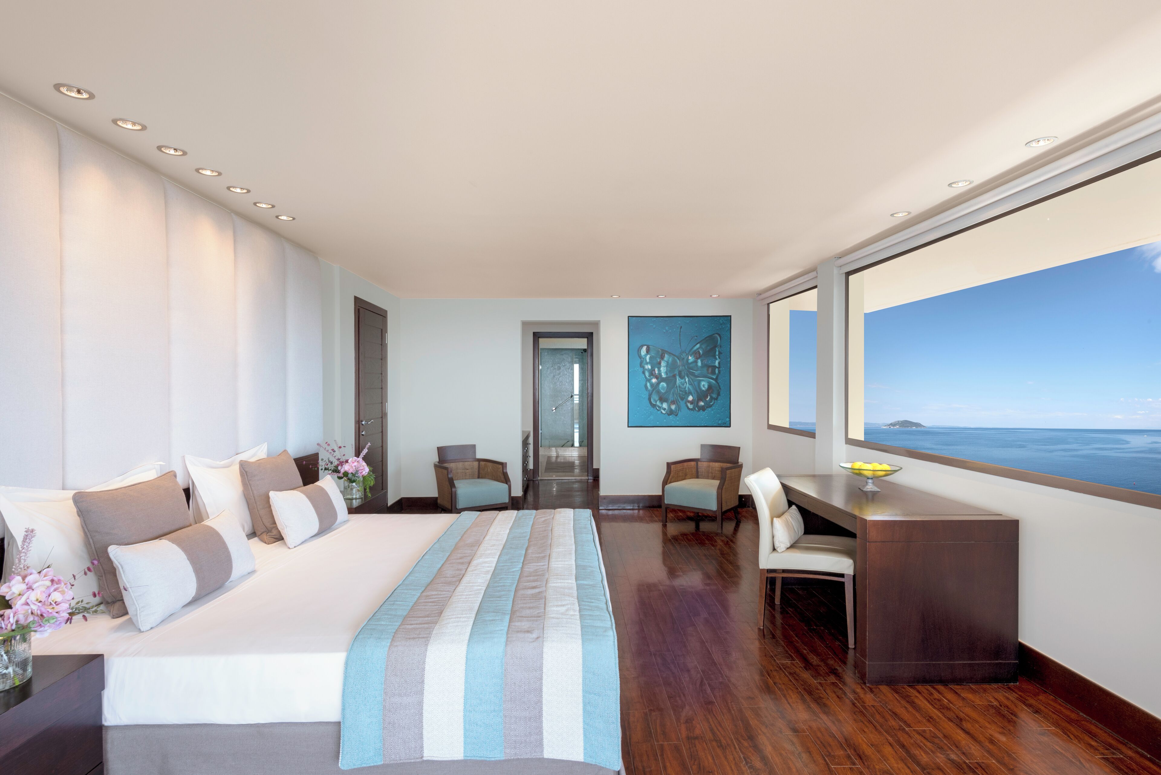 Una habitación de hotel moderna con una cama grande, un escritorio y vistas al océano.