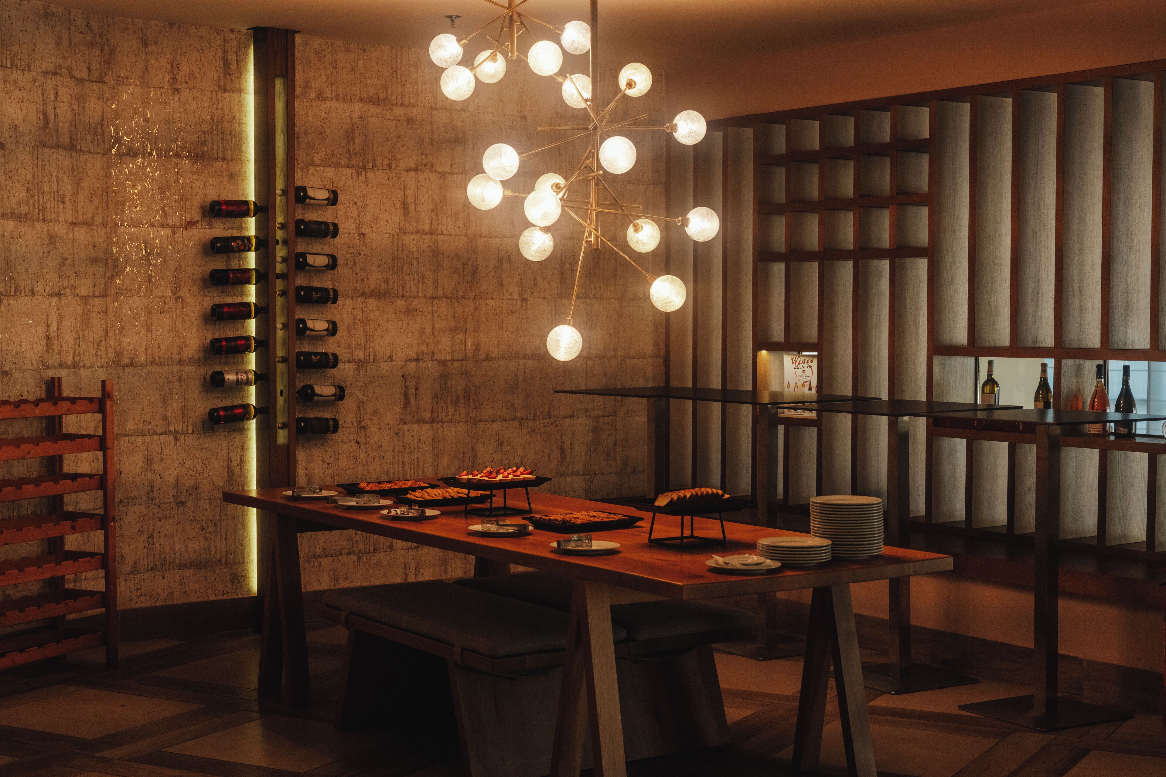 A modern dining area with a long table, multiple seating options, and a unique light fixture.