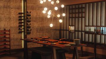 A modern dining area with a long table, multiple seating options, and a unique light fixture.