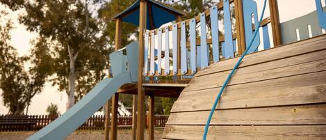 Une structure de jeu en bois, dotée d’un toboggan et d’une zone d’escalade.