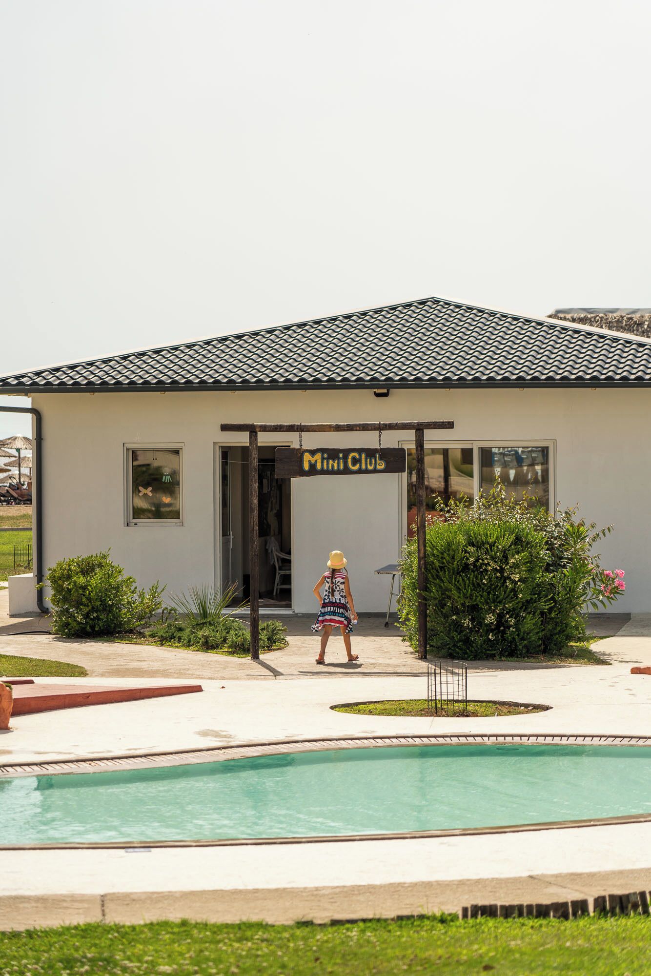 A building with a sign reading "Mini Club" and a swimming pool in front.