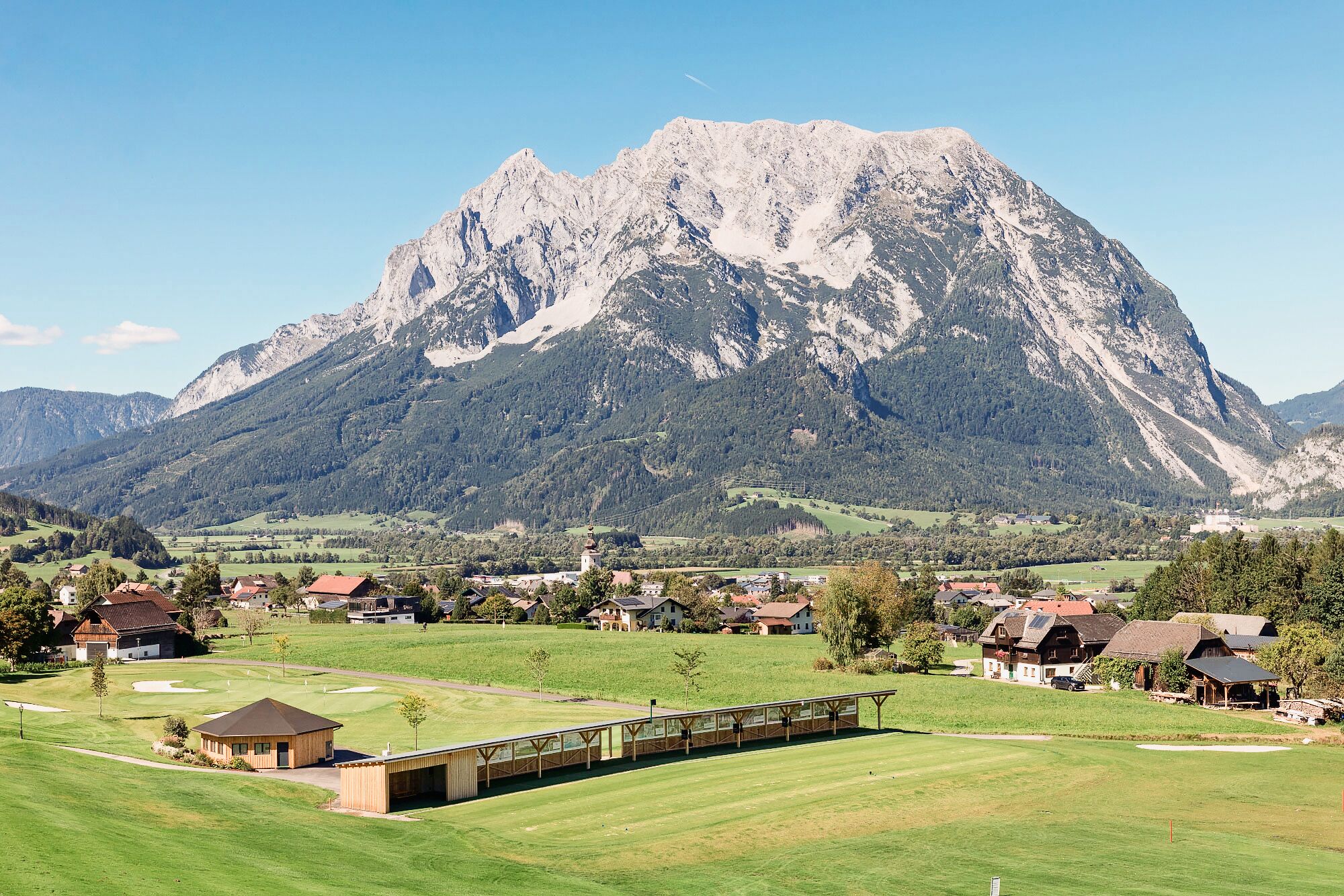 Un paysage de montagne avec un village, des maisons et un terrain de golf.