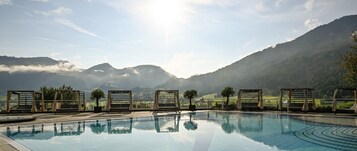 Una piscina con sillas de descanso y vistas a las montañas.