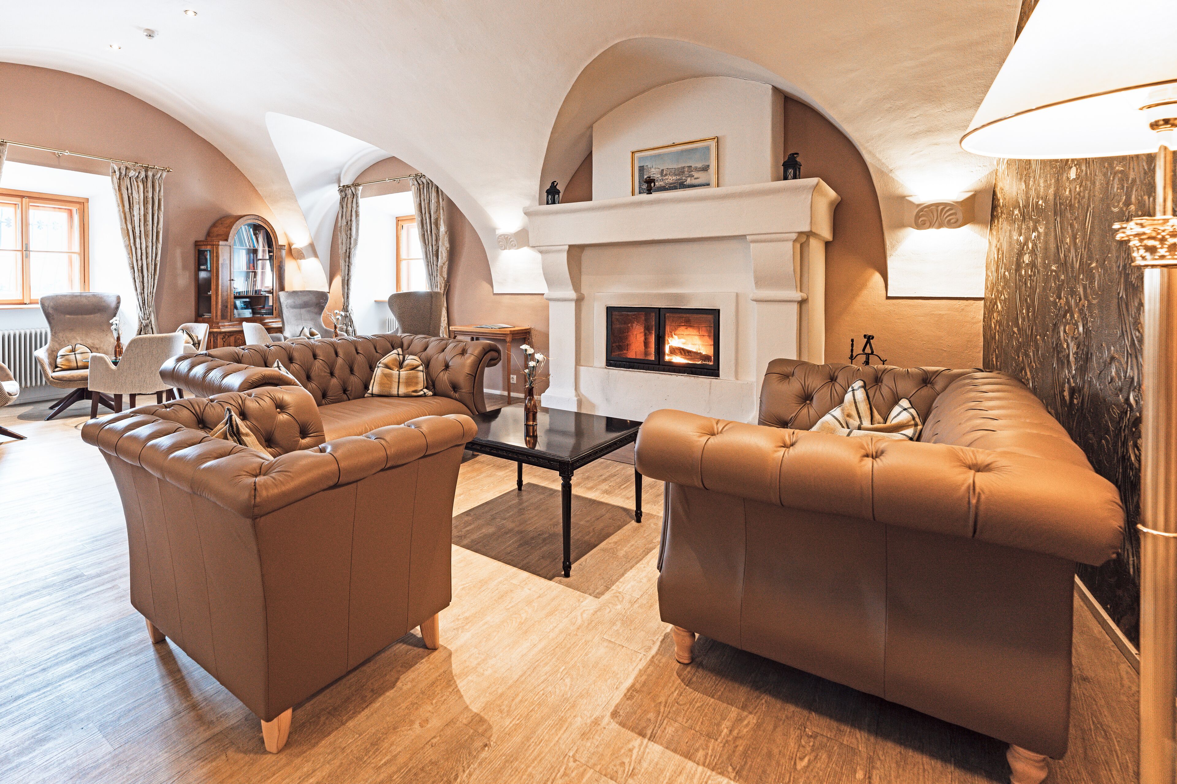 A spacious living room with leather sofas, a fireplace, and a high arched ceiling.