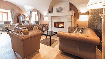 A spacious living room with leather sofas, a fireplace, and a high arched ceiling.