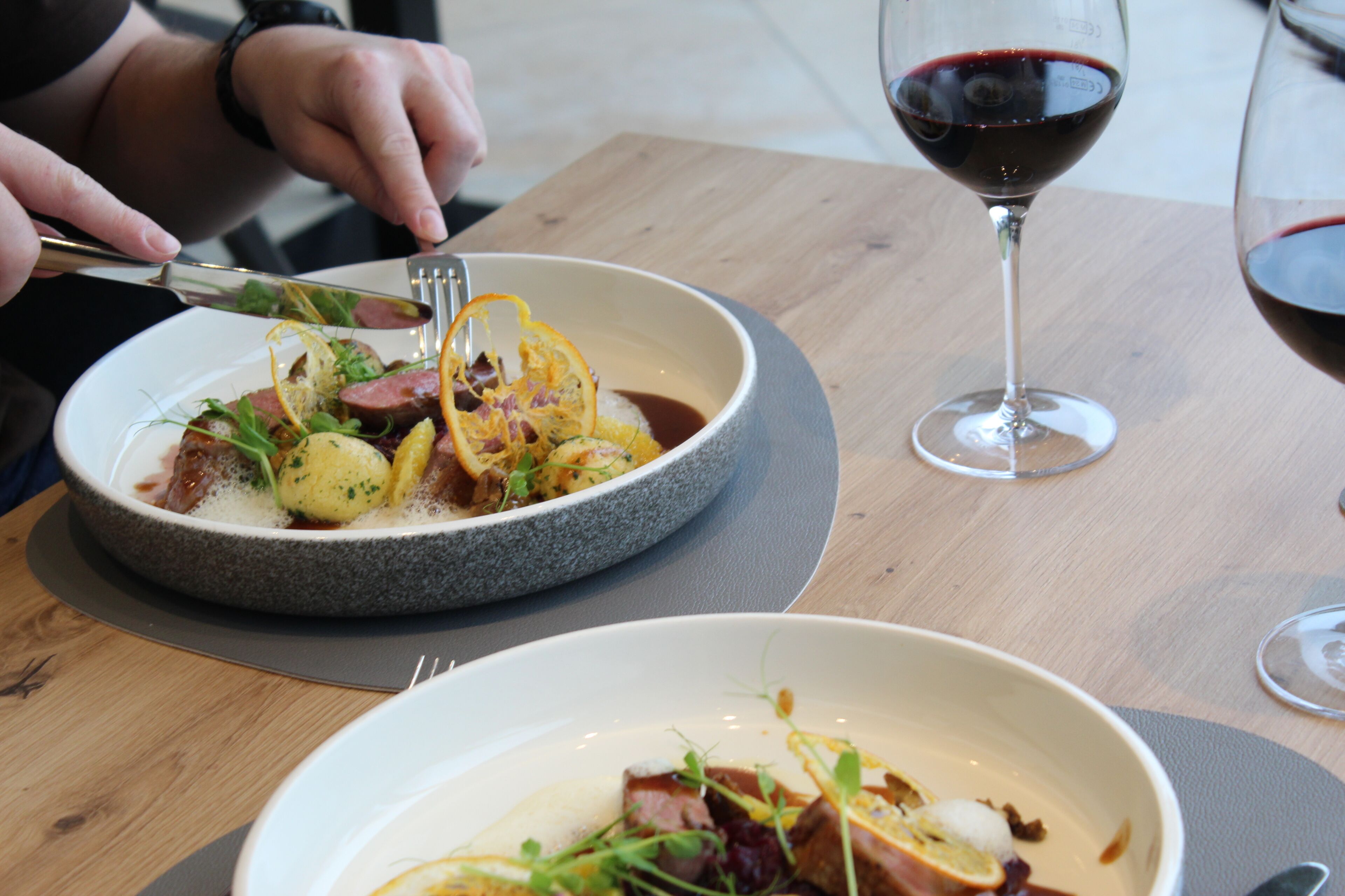 A dining table with a plate of food and a glass of red wine.