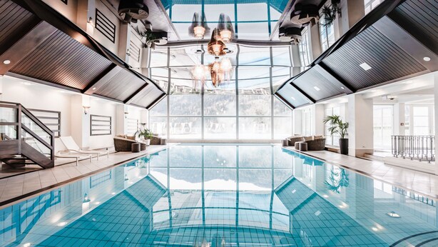 A large indoor swimming pool with a clear view of the outdoors through the ceiling.