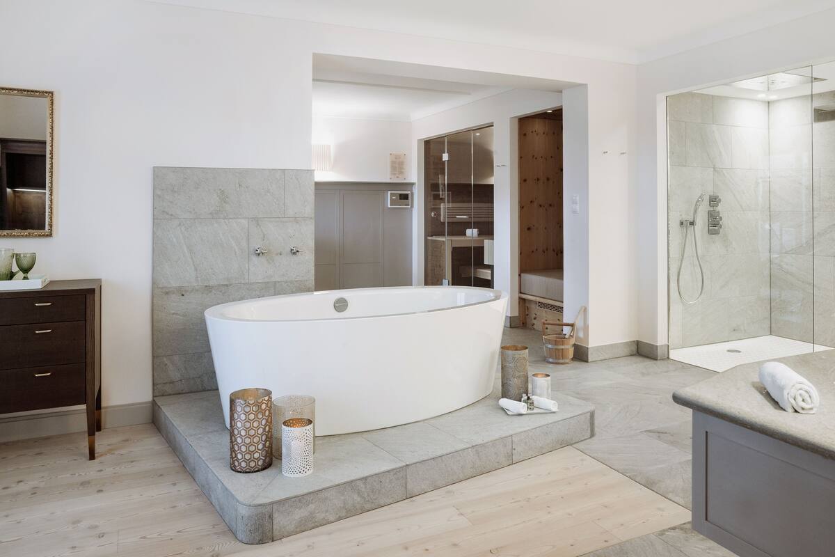 Un bany modern amb una banyera independent, dutxa sense barrera i un lavabo amb mirall.