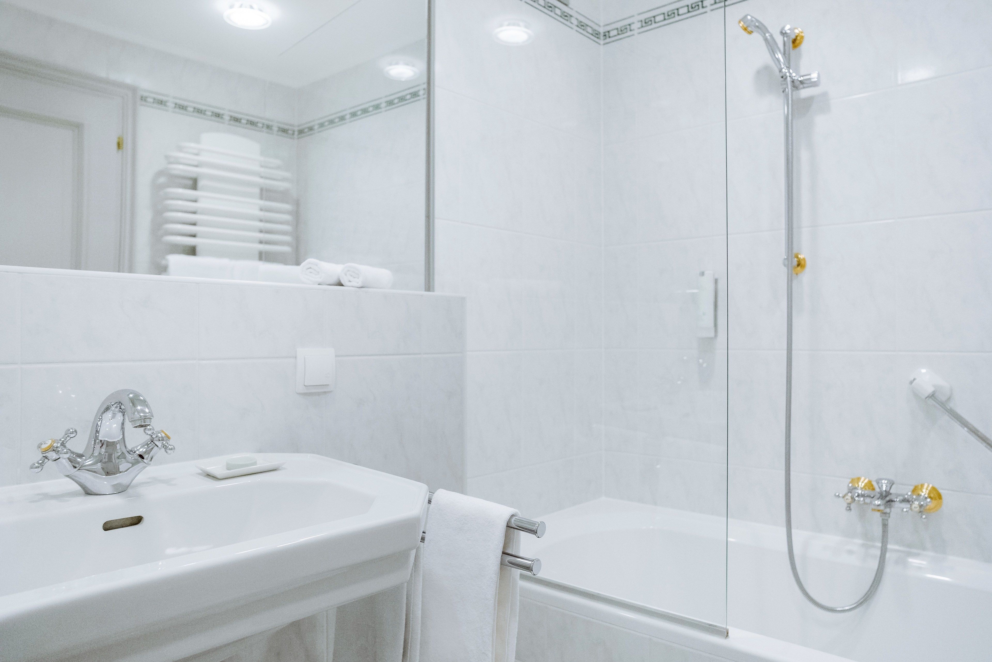 A modern bathroom with a white sink, mirror, and shower.