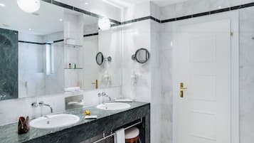Ein modernes Badezimmer mit zwei Waschbecken, einem großen Spiegel und einer Tür mit goldener Griff.