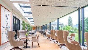 A modern indoor space with high ceilings, large windows, and a variety of seating arrangements.