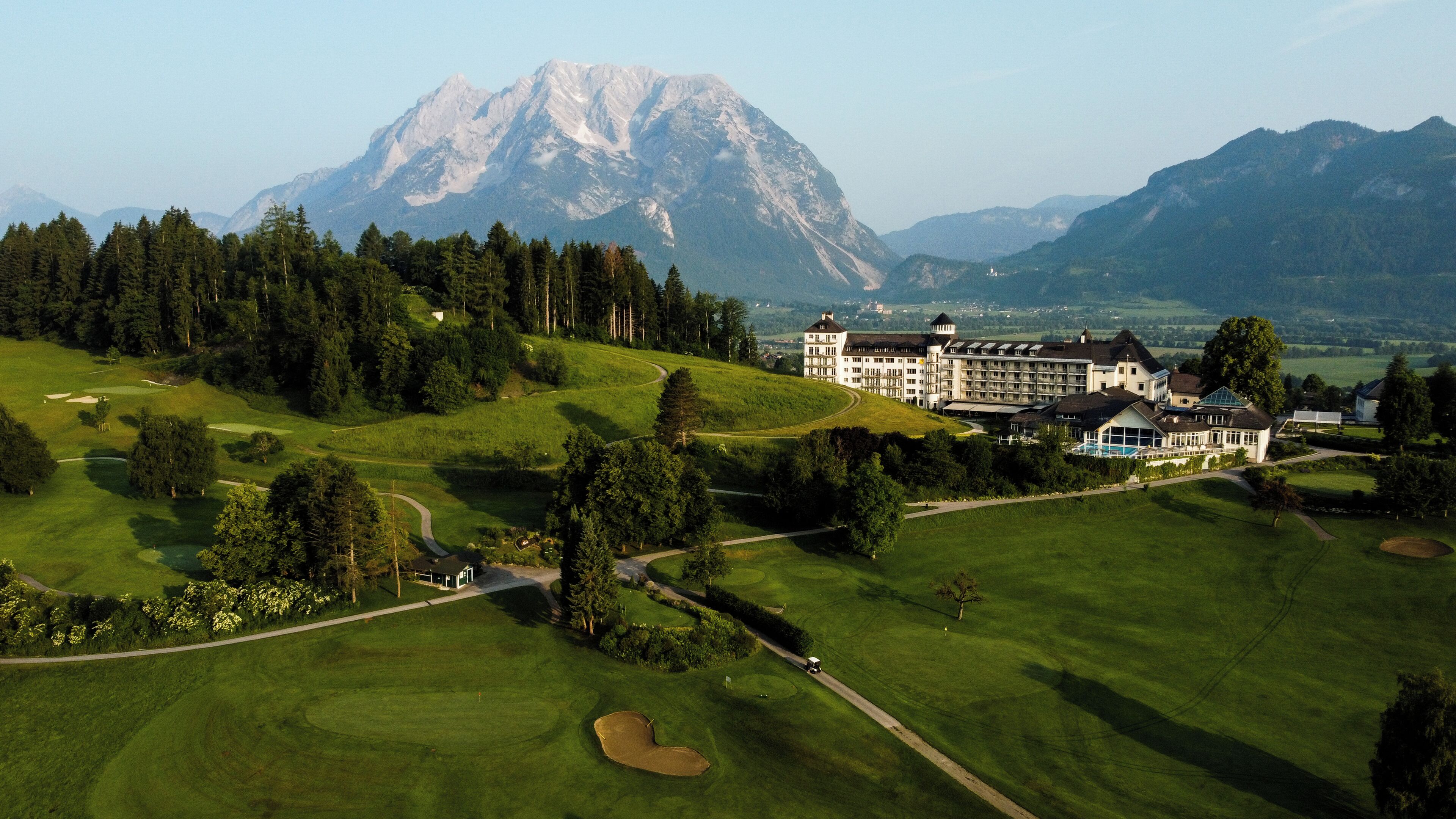 Un campo da golf con un edificio grande sullo sfondo, probabilmente un hotel.
