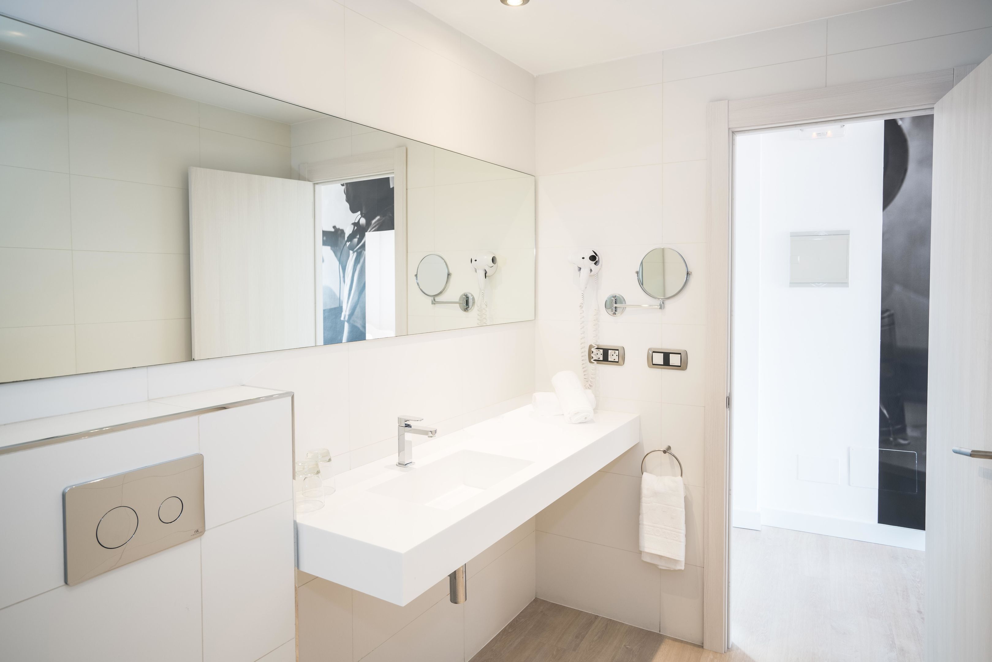 Une salle de bain moderne avec un grand miroir, deux lavabos et un porte-serviettes.