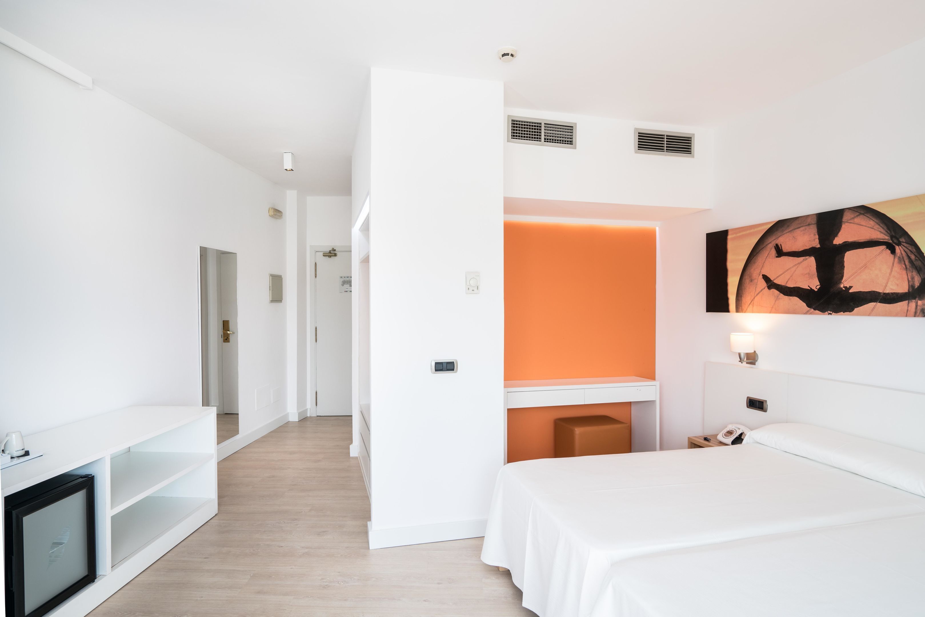 A modern hotel room with a bed, a desk, and a television.