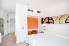 Una camera d'albergo con un letto, una scrivania e un'opera d'arte appesa al muro.