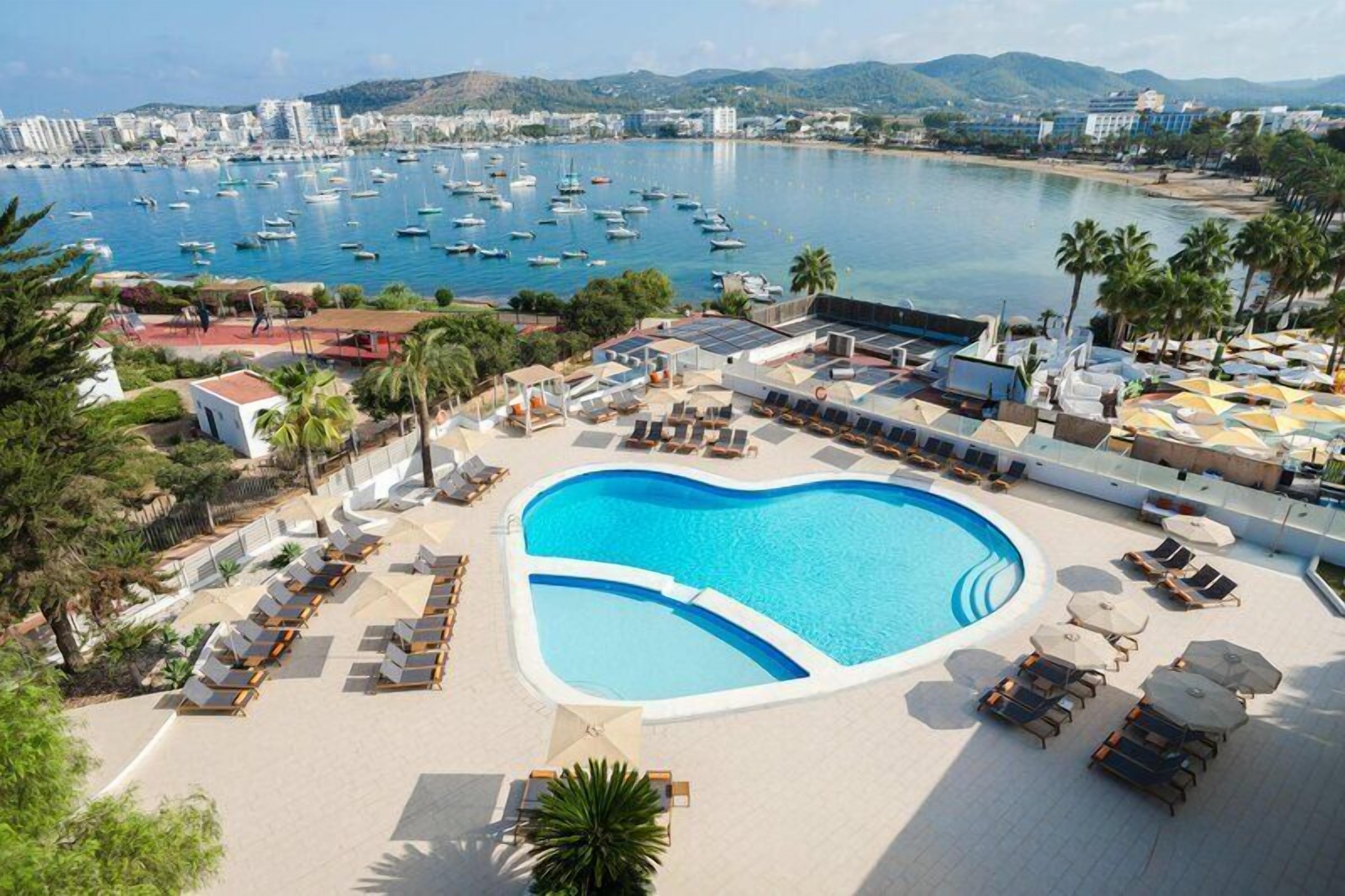 Una piscina al aire libre, sombrillas, tumbonas