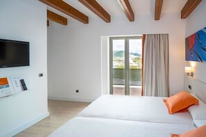 A hotel room with a bed, a TV, a window with curtains, and a view of the outside. - Hotel THB Ocean Beach - Adults Only (Sant Antoni de Portmany)