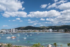A coastal town with a marina filled with boats, a beach, and a backdrop of hills. - Hotel THB Ocean Beach - Adults Only (Sant Antoni de Portmany)