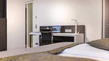 Een hotelkamer met een bed, een bureau, een stoel en een computer monitor.