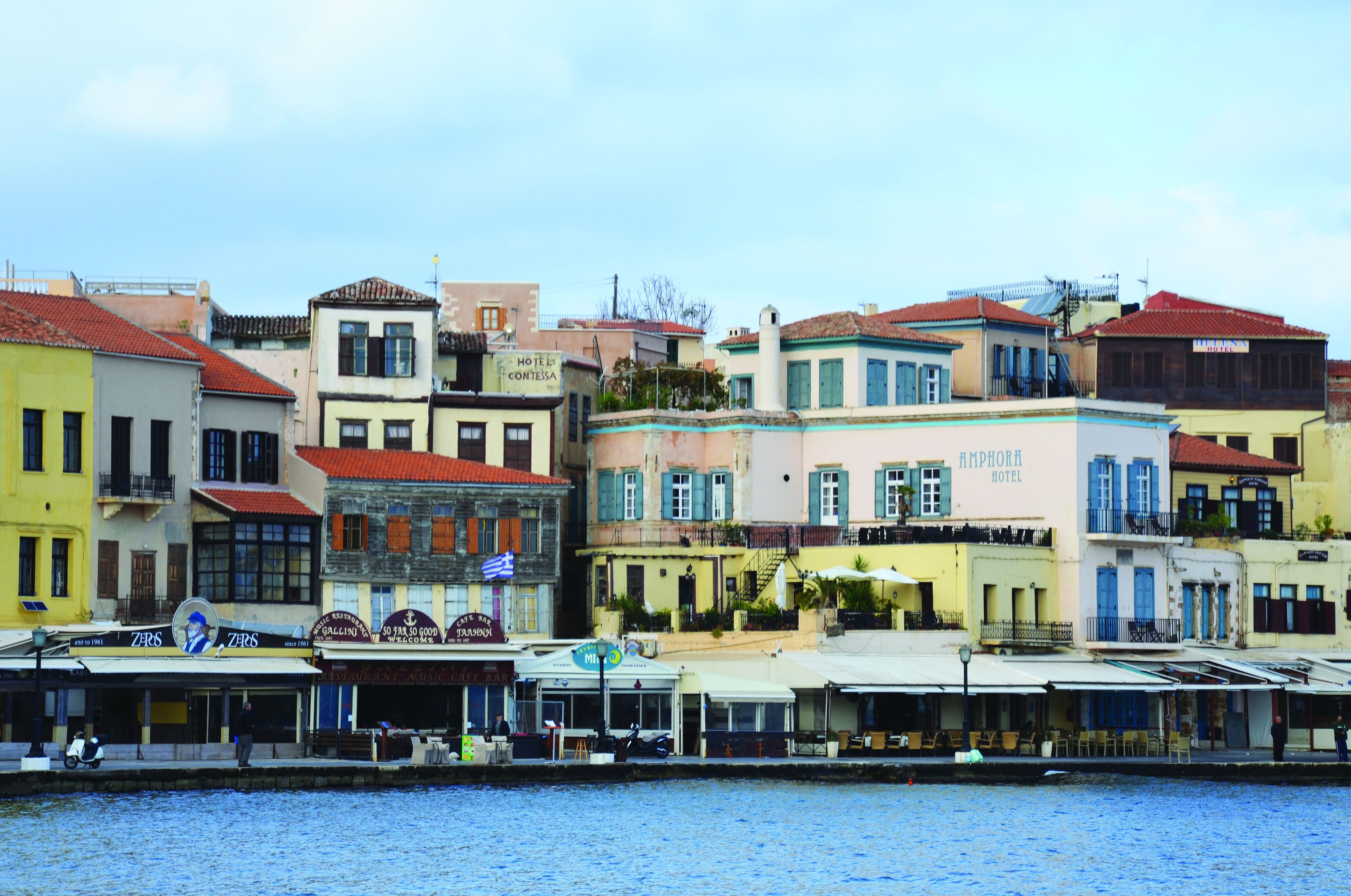 Un hotel frente al agua con varios pisos, balcones y un letrero que dice 'Amphora Hotel'.
